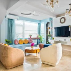 Celeste - Vio Stays - 3BHK Luxury Private Pool Villas In Baga - Living room/hall with television, 8-seater sofa, centre table, flower pot, paintings, window, curtains, & fan.