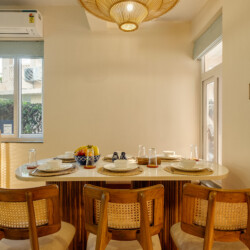 Ina - Villa in Siolim Goa dining table for 6 to 7 people with lights, plates, glasses and fruits.