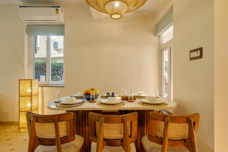 Ina - Villa in Siolim Goa dining table for 6 to 7 people with lights, plates, glasses and fruits.
