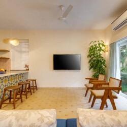 Ina - Private Pool Villa in Siolim Goa - Living room with 2 cosy chairs television, bar stools and part view of kitchen
